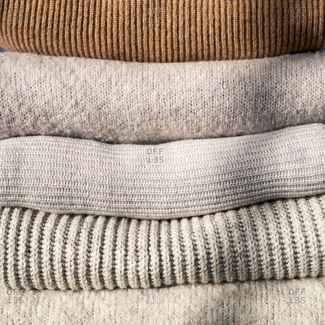 Pile of folded neutral-colored sweaters stock photo - OFFSET