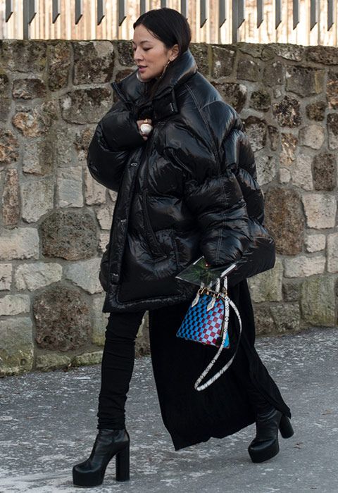 A street style image of a black oversized puffer jacket, boots
